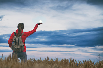 Tourist woman standing in field  and trying catch the full moon  to her hand