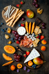Appetizers table with italian antipasti snacks. Cheese and charcuterie variety board over rustic wooden background