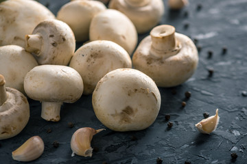 Fresh white Champions, spices and ingredients on the dark kitchen table. Concept of cooking mushroom dishes