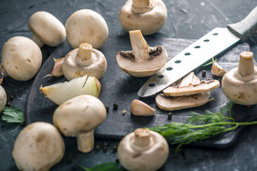 White champignons cut in half with a knife and the ingredients. Concept of cooking mushroom dishes. Close up