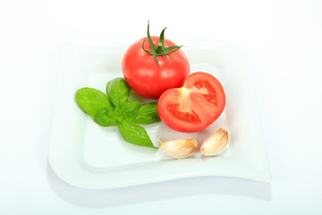 Pomidor, czosnek i liście bazylii na białym tle.