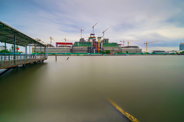 Fototapeta na wymiar Building construction site and cranes beside the river, Long exposure