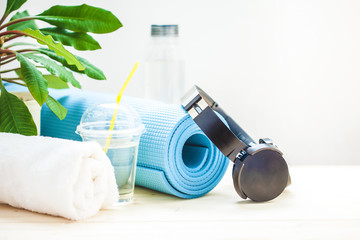 set for sports. Blue yoga mat towel headphones and a bottle of water on a light background The concept of a healthy lifestyle Copy space.