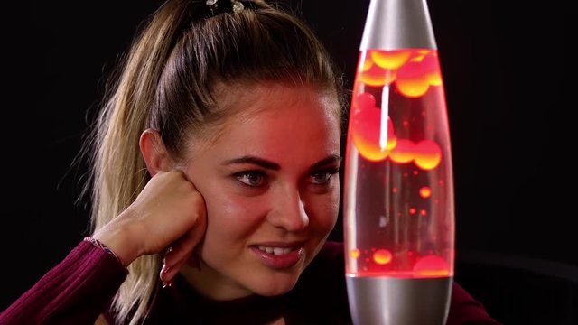 Pretty woman looking at a lava lamp.