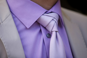 Dettaglio abito da sposo con camicia viola, giacca grigia, cravatta viola, 