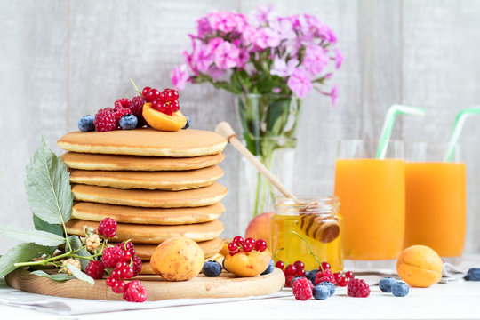 Fresh delicious pancakes with summer berries on light background.