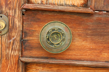 A vintage round handle on a brown shabby wooden door. Lindos, Rhodes, Greece