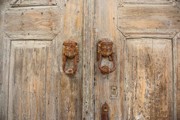Vintage handles with faces on a wooden door. Lindos, Rhodes, Greece