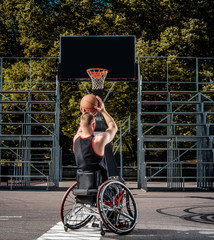 Cripple basketball player in a wheelchair plays on open gaming ground.