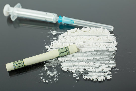 Syringe for heroin and cocaine powder on black background, drug abuse concept.