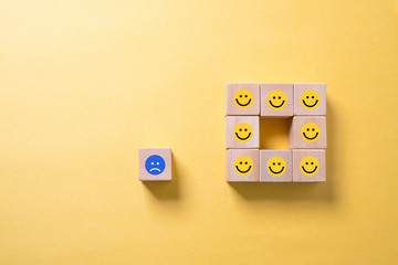 Viele Würfel mit lächelnden Smileys und einer der unzufrieden ist 