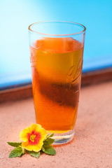 Ein orangefarbener Drink am Pool, dekoriert mit orangegelber Blüte