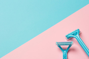 two disposable blue razors on pink background