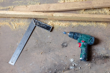 Screwdriver and ruler are on the dirty and dusty wooden floor in room is under construction,...