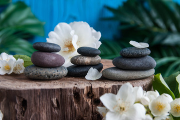 Pyramids of gray zen stones with beautiful fresh white flowers. Concept of harmony, balance and meditation, spa, massage, relax