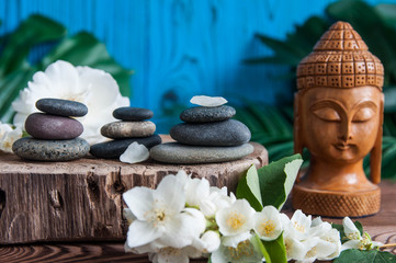 Pyramids of gray zen stones with beautiful fresh white flowers and Buddha statue. Concept of...
