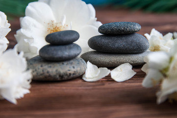 Fototapeta na wymiar Pyramids of gray zen stones with beautiful fresh white flowers. Concept of harmony, balance and meditation, spa, massage, relax