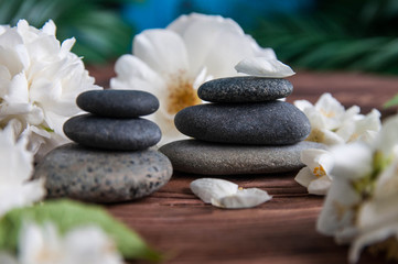 Obraz na płótnie Canvas Pyramids of gray zen stones with beautiful fresh white flowers. Concept of harmony, balance and meditation, spa, massage, relax