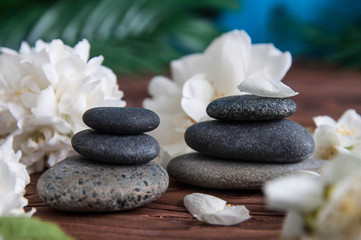 Obraz na płótnie Canvas Pyramids of gray zen stones with beautiful fresh white flowers. Concept of harmony, balance and meditation, spa, massage, relax