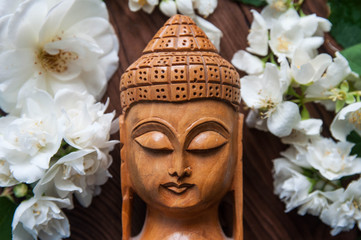Wooden Buddha statue with beautiful fresh white flowers. Concept of harmony, balance and meditation, spa, massage, relax