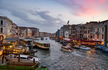 Canal Grande with boats and lights in Venice at Sunset. Next to famous Rialto Bridge and the Street "Riva del fin" - Italy