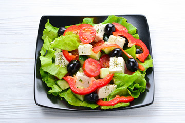 Greek salad on a white wooden background. Space for text or design.