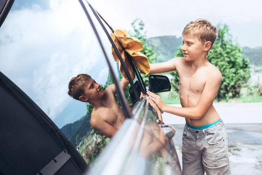 Boy helps with car washing: rubes windows to shine