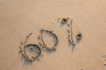 Sessanta percento scritto sulla sabbia bagnata in riva al mare