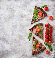 Pieces of  black pizza with tomatoes and basil