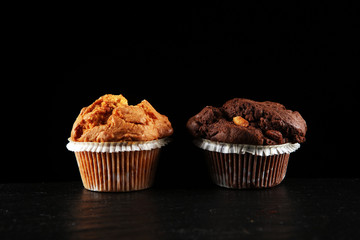 Chocolate muffin and nut muffin, homemade bakery on dark background.