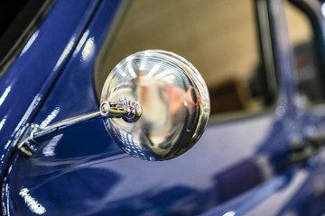 Close-up the side mirror of a blue old car. Rear-view mirror.