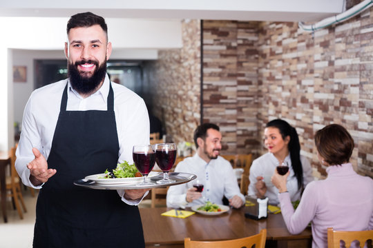 happy waiter serving dear restaurant guests