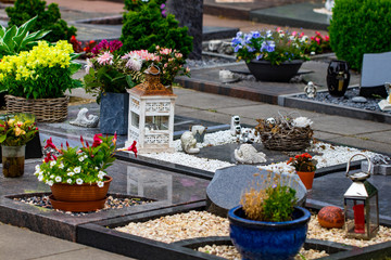 Headstones in a cemetery with many different flowers