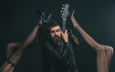 Music is his passion. Bearded man with guitar tempted by sexy legs in fetish lingerie. Feeling flirty. Like rock star. Attractive and sensual