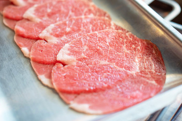 Raw sliced beef on stainless tray.