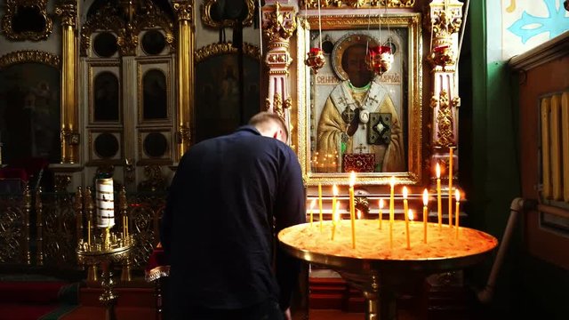 A man prays and worships the icon of St. Nicholas. A man in a Christian Church.