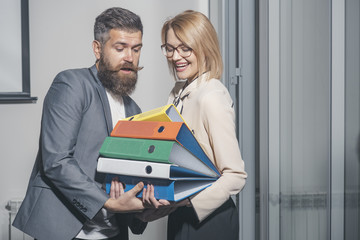 Office romance and flirt concept. Man help woman to carry binders in office. Businesswoman and...