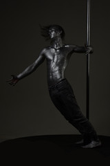 Strong dancer workout on pole. Freedom. Sexy macho with metal skin. Muscular man with silver body...