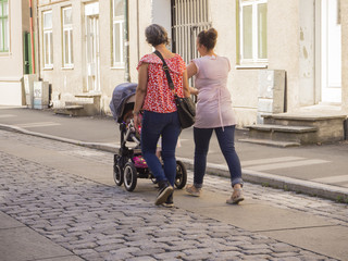 Fototapeta premium Pareja de mujeres gays paseando un bebé en un cochecito, en Noruega, verano de 2017