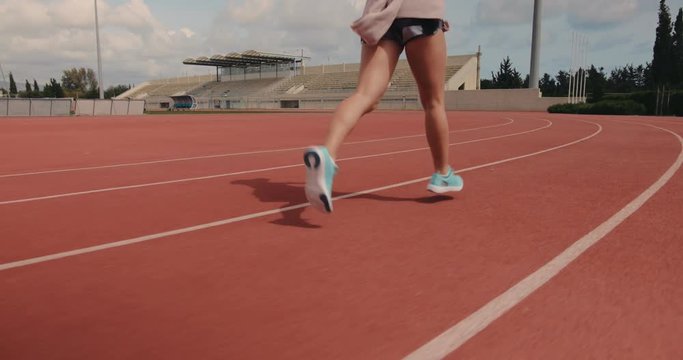 Young female runner practising and running on stadium track