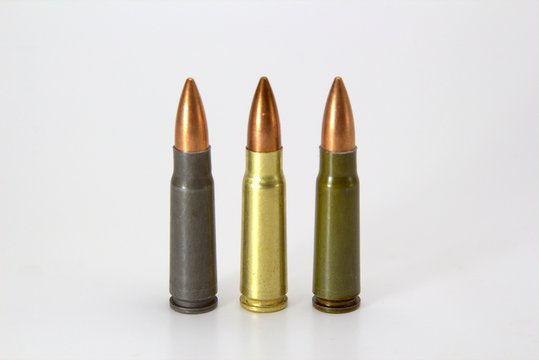 three multi-colored cartridge 7.62 by 39 on white background close-up