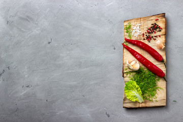 Cooking background concept - cutting board and spices on a gray stone background. Top view. Copy space.