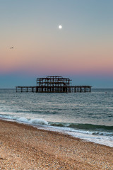 Brighton's West Pier at sunset, with a full moon overhead