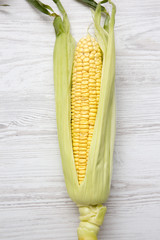 Ear of corn on a white wooden background, top view. From above, flat lay.