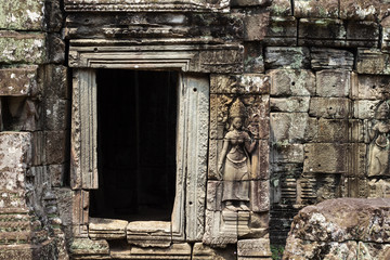 Fototapeta na wymiar Ancient stone bas-relief of Banteay Kdei temple, Angkor Wat, Cambodia. Ancient temple door with stone carving.