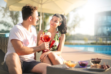 People drinking a cocktail next to a swimming pool