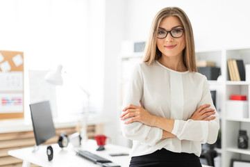 A young girl is standing leaning on a table in the office.