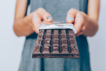 Woman's hands holding unwrapped dark chocolate bar