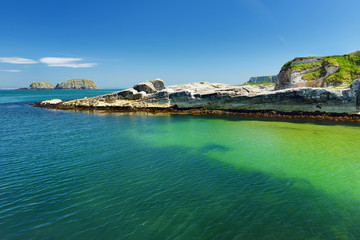 Obraz premium Vivid emerald-green water at Ballintoy harbour along the Causeway Coast in County Antrim, Northern Ireland.