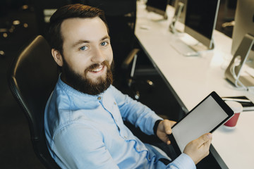 Smiling man sitting in office with tablet